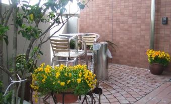 a small courtyard with a potted plant , a metal watering can , and several chairs placed around it at Toyota Village