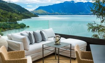 a white couch and chairs are on a patio overlooking a lake with mountains in the background at Rosewood Matakauri