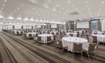 The ballroom at the hotel has been arranged for a wedding, with round tables and chairs facing each other at Rydges Resort Hunter Valley, an EVT hotel