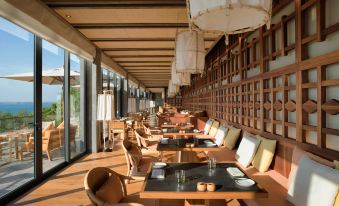 an outdoor dining area with wooden tables and chairs , creating a warm and inviting atmosphere at Six Senses Krabey Island