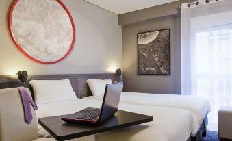 a modern bedroom with a bed , a laptop on the bedside table , and a round painting above the bed at Ibis Styles Paris Mairie de Montreuil