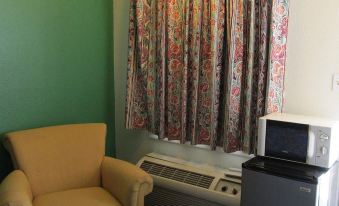 a small living room with a yellow chair , an air conditioner , and a television mounted on the wall at Village Inn