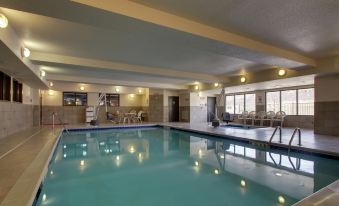 an indoor swimming pool with a large , empty pool in the center , surrounded by chairs and tables at Hampton Inn & Suites Denver Littleton