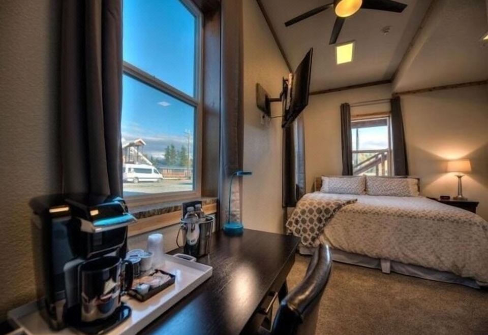 a hotel room with a large window overlooking the mountains , a bed , and a desk with a coffee maker at The Cannery Lodge