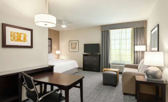 a hotel room with a bed , desk , chair , and couch , along with a television and a television in the corner at Homewood Suites by Hilton Frederick