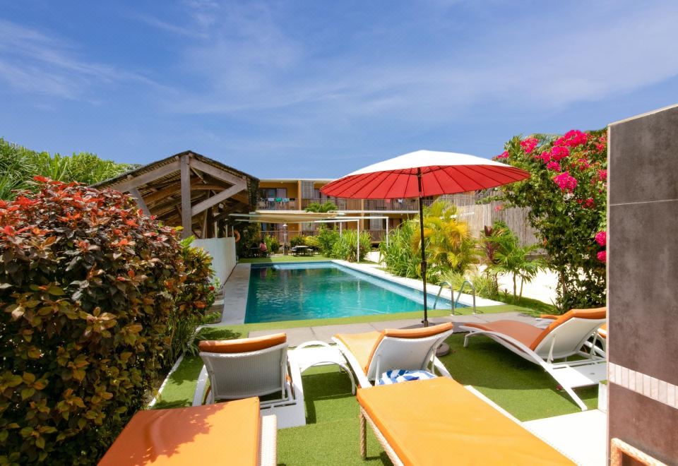 a backyard with a swimming pool surrounded by chairs and umbrellas , creating a relaxing atmosphere at Reef Beach Resort