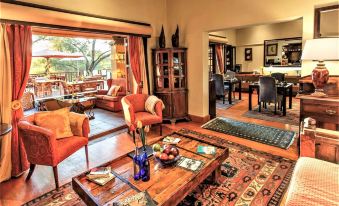 a cozy living room with wooden furniture , including a couch , chairs , and a dining table at Riverside Guest Lodge