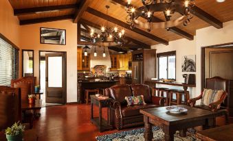 a spacious living room with wooden beams on the ceiling , a couch , and a dining table at La Lomita Ranch