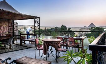 a patio with a dining table , chairs , and umbrellas , overlooking a scenic view of the desert at Pyramids View Inn