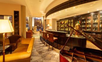 a well - lit hotel lobby with a bar and seating area , surrounded by windows that offer a view of the city at Hotel Continental