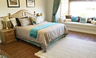 a well - decorated bedroom with a large bed , two couches , and a rug on the hardwood floor at Country Comfort