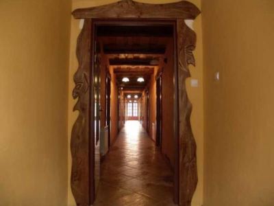 a long , narrow hallway with wooden doors and walls , leading to a brightly lit room at the end at Troll