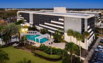 an aerial view of a large hotel with a pool and palm trees in front of it at Sheraton Orlando North Hotel