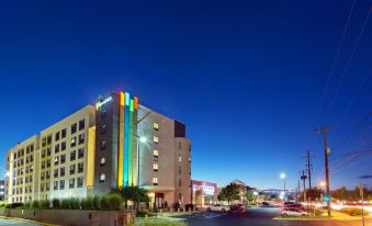 a modern building with colorful lights is located in a city at night , surrounded by other buildings at Even Hotel Rockville - Washington, DC Area, an IHG Hotel