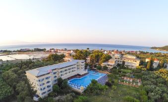 a large hotel complex with a swimming pool , surrounded by trees and situated near the ocean at Koukounaria Hotel & Suites
