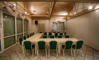 a conference room with a large table surrounded by green chairs and a skylight in the ceiling at Hotel Rosengarten Leipzig-Naunhof