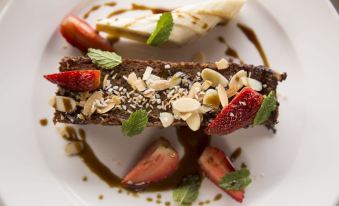 a dessert with a slice of chocolate cake , strawberries , and almonds is presented on a white plate at Hotel Belmar