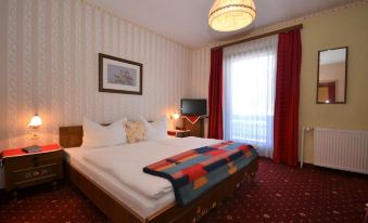 a well - decorated hotel room with a bed , curtains , and a window , along with a tv and other amenities at Berghof