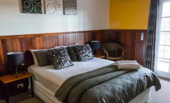 a well - decorated hotel room with a large bed , wooden headboard , and two chairs near the window at Nannup Hideaway