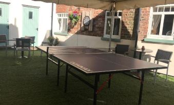 a brown ping pong table is set up on a patio , surrounded by chairs and a brick building at The Mansion House Hotel