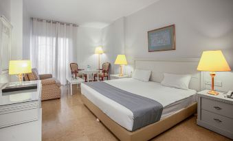 a large bed with white and gray bedding is in a hotel room next to two chairs and a table at Grand Hotel Madaba