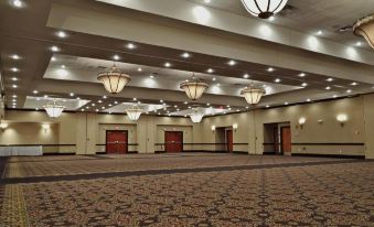 a large , empty conference room with multiple chandeliers hanging from the ceiling and multiple doors on either side at Hilton Garden Inn Kankakee