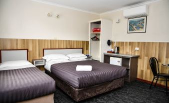 a hotel room with two beds , a nightstand between them , and a closet in the background at Hobart Tower Motel