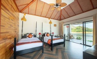 a room with two beds , one on each side of the room , and a ceiling fan at Phong Nha Lake House Resort