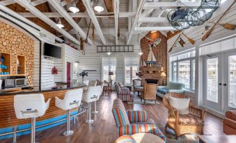 a spacious , modern - style living room with wooden floors , white walls , and large windows , featuring a bar area , multiple chairs , and at Hilton Grand Vacations Club Blue Mountain Canada