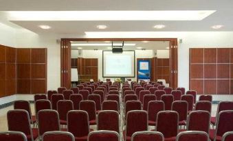 a conference room with rows of red chairs arranged in a semicircle , and a projector on the wall at Valamar Bellevue Resort