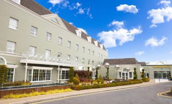 a large hotel with a white exterior and many windows is surrounded by bushes and trees at Hillgrove Hotel, Leisure & Spa