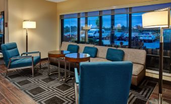 a seating area in a hotel lobby , with blue chairs and couches arranged around a coffee table at TownePlace Suites Detroit Belleville