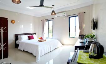 a white bedroom with two beds , one on the left and one on the right side of the room at Pink Beach Homestay
