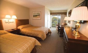 a hotel room with two beds , a desk , and a sliding glass door leading to a balcony at Pinestead Reef Resort