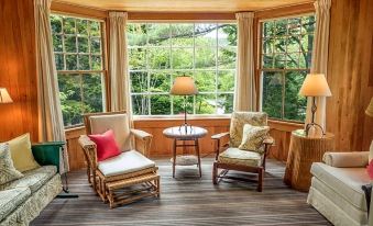 a cozy living room with two chairs , a table , and a view of trees through the window at Harbourside Inn