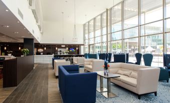a modern , spacious lobby with multiple couches and chairs , creating a comfortable and inviting atmosphere at Hampton by Hilton Oswiecim