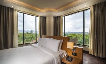 a large bed with white sheets is in a room with windows overlooking the city at Hyatt Place Hampi