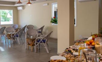 a dining room with a long wooden table filled with food , surrounded by chairs and potted plants at Hotel Royal