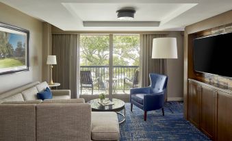a living room with a blue chair , a gray couch , and a coffee table in front of a large window at The Grand Hotel Golf Resort & Spa, Autograph Collection