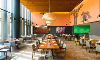 a large dining room with wooden tables and chairs arranged for a group of people at Radisson Hotel, Dakar Diamniadio