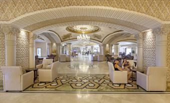 a luxurious hotel lobby with marble floors , white chairs , and a chandelier hanging from the ceiling at Royal Alhambra Palace