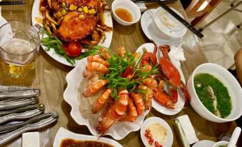 a table is filled with various dishes , including crab legs and a bowl of sauce at Hai Tien Plaza Hotel
