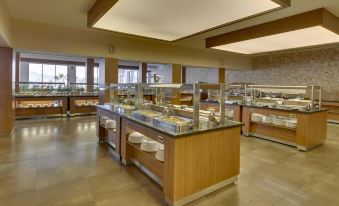 a large , modern restaurant with a long buffet table filled with various food items and utensils at Armonia Holiday Village & Spa