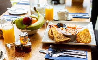 a dining table with a variety of food items , including fruits , bread , and other breakfast items at Grapes Hotel, Bar & Restaurant Snowdonia Nr Zip World