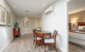 a modern , minimalist living room with white walls and wooden floors , featuring a dining table and chairs , a couch , and an air conditioner at Red Lion Inn and Suites Victoria