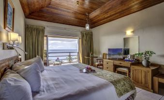 a bedroom with a large bed , wooden ceiling , and a view of the ocean through a window at Grafton Beach Resort