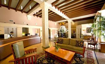 a spacious living room with wooden columns , a couch , chairs , and a dining table , all decorated in a traditional style at Hotel Carmel Santa Monica