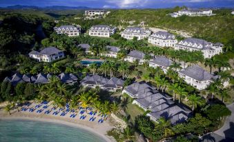 aerial view of a beach resort with multiple buildings and palm trees surrounding the water at Residences at Nonsuch Bay Antigua