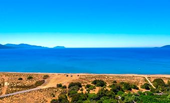 a scenic view of a beach with blue water and distant mountains , captured from a high vantage point at Paradise Resort