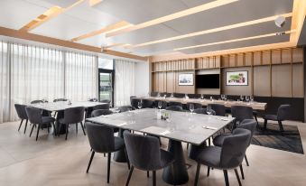 a modern conference room with a long table , multiple chairs , and large windows , ready for meetings or events at Hilton Garden Inn Silverstone